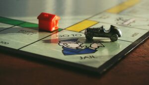Close-up shot of a Monopoly board game featuring a toy car and a red house on 